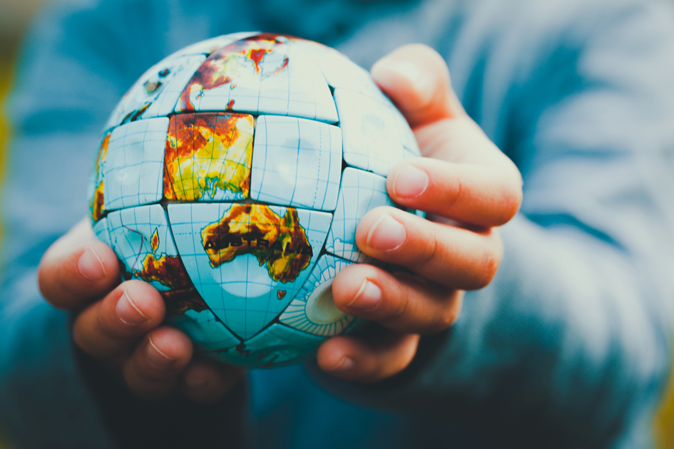 Handen die een wereldbolpuzzle vasthouden — symbool voor verandering en een wereld van verschil
